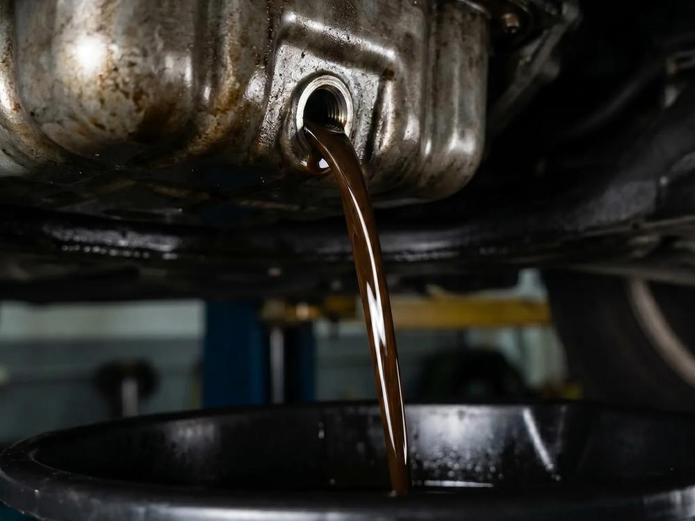 Used engine oil draining into a pan